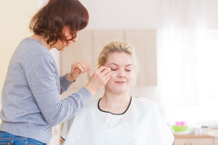 Cosmetic beauty procedures and makeover concept. Woman face painting. Makeup artist working on model, applying base foundation liquid powder.の写真素材