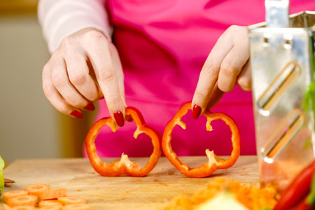 Cooking woman showing two red bell pepper paprika rings, sliced healthy vegetable, salad ingredient.の写真素材