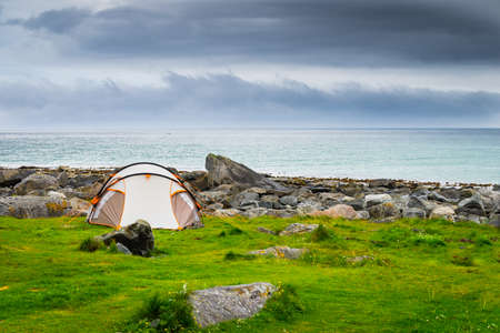 Tent on seashore in summer, cloudy hazy weather. Camping on ocean shore. Skagsanden Beach Flakstadoy Lofoten Norway. Holidays travel and adventure.の写真素材