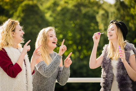 Vacations joy, friendship concept. Women friends having fun blowing soap bubbles outdoor.の写真素材