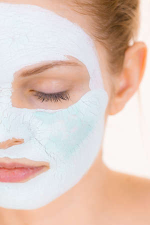 Young woman with white green mud mask on face. Teen girl taking care of oily skin, purifying the pores. Beauty treatment. Skincare.の写真素材