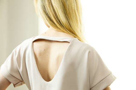 Unrecognizable woman presenting fashionable pink top with hole detail on her back.の写真素材