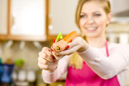 Woman peeling vegetables using food peeler. Cooking female preparing carrot before serving.の写真素材