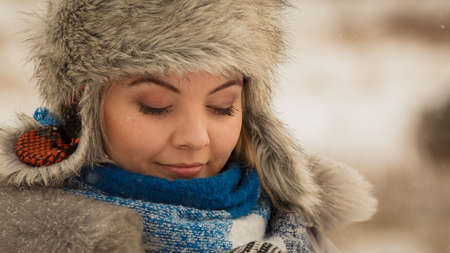 Pretty young woman wearing warm accessories during winter time. Female having grey warm hat made of light fur and blue scarf.の写真素材