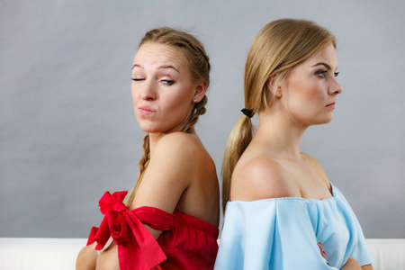 Two suspicious female friends having thinking face expressions, being angry at each other.の写真素材