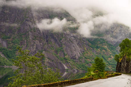 Norwegian landscape. Old road along fjord Eidfjorden in Norway Hordaland. Foggy rainy weather.の写真素材
