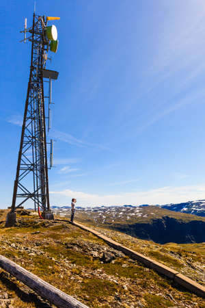 Telecommunications tower mast wireless technology in mountains and tourist woman enjoying mountain view landscapeの写真素材
