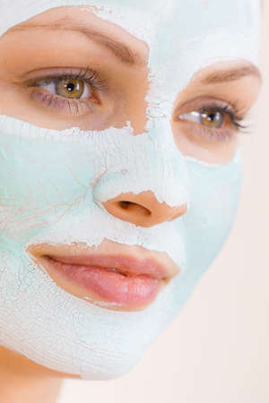 Young woman with white green mud mask on her face. Teen girl taking care of oily skin, cleaning the pores. Beauty treatment. Skincare.の写真素材