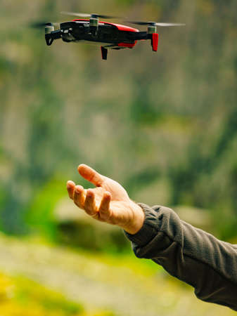 Start the drone, launching from hands. Modern small copter with camera in user hand, against nature. Technological equipment.の写真素材