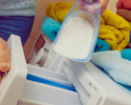 Female hand pour the washing powder detergent into machine.の写真素材