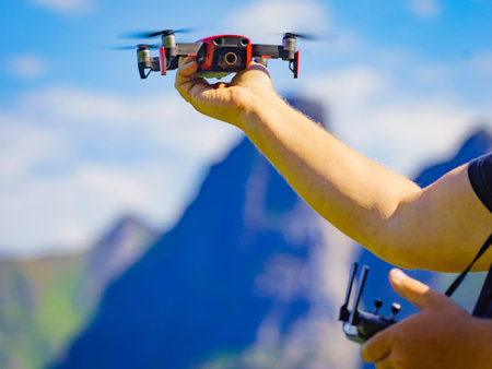 Start the drone, launching from hands. Modern small copter with camera in user hand, against sky....