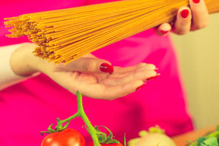 Woman holding long pasta macaroni ready to cook spaghetti. Healthy food concept.の写真素材