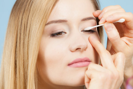 Visage concept. Close up woman getting make up on eyelids. Applying eyeshadow with q tip by professional artistの写真素材