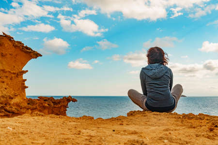 Tourist adult woman relaxing on yellow sand formations of Cocedores Beach. Mediterranean sea, Murcia region Spain.の写真素材