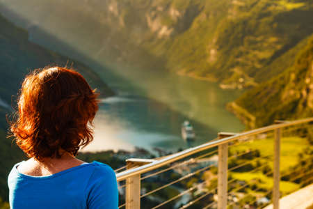 Tourist woman enjoying scenic view over fjord Geirangerfjord from Flydalsjuvet viewpoint. Cruising vacation and travel.の写真素材