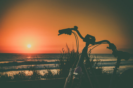 Bicycle outdoor parked on beach, evening time, sunset sky. Holidays, sport and recreation.の写真素材