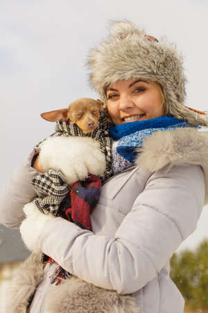 Young woman wrapped her best friend little dog in warm blanket scarf to warm him in cold winter day. Animal protection save. Adoption conceptの写真素材