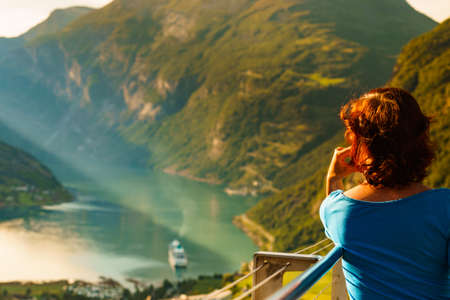 Tourist woman enjoying scenic view over fjord Geirangerfjord from Flydalsjuvet viewpoint. Cruising vacation and travel.の写真素材