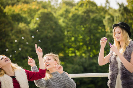 Vacations joy, friendship concept. Women friends having fun blowing soap bubbles outdoor.の写真素材
