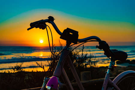 Bicycle outdoor parked on beach, evening time, sunset sky. Holidays, sport and recreation.の写真素材