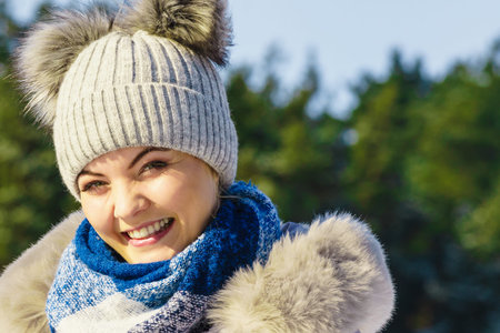 Pretty young woman wearing warm accessories during winter time. Female having grey beanie warm hat...
