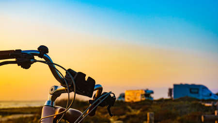 Bicycle outdoor parked on beach, evening time, sunset sky. Holidays, sport and recreation.の写真素材