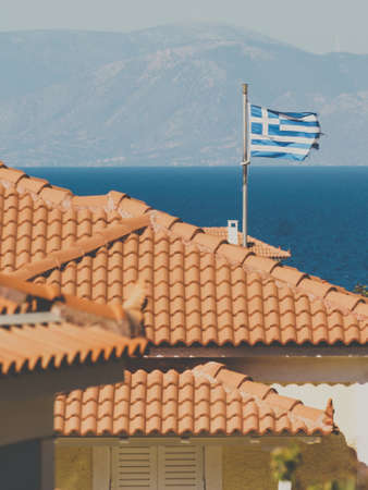 White blue state flag of Greece on roof of private estate, tourist house in seaside Mediterranean town.の写真素材