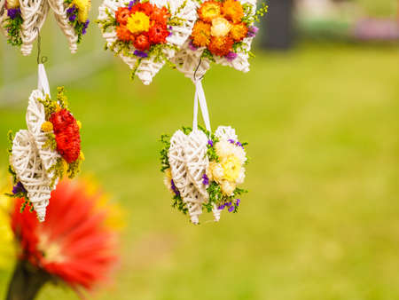 Decorative hanging hearts made of white wicker and flowers. Art, folk decorations concept.の写真素材