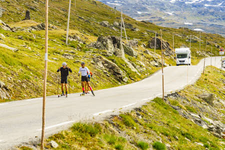 SOGNEFJELLET, NORWAY - JULY 7, 2018: People riding on roller skis in mountains on National Tourist Route Sognefjellet. Summer training exercise on rollerskis.のeditorial素材