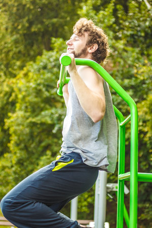 Active young man exercising on ladder. Muscular sporty guy in training suit working out at outdoor...