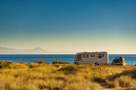 Camper on sea coast with with little car on platform, Spain. Camping on nature beach. Holidays and traveling in motor home.の写真素材