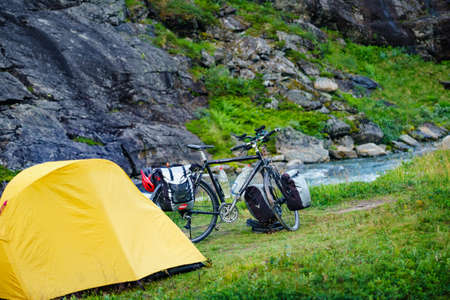 TROLLSTIGEN, NORWAY - JULY 27, 2018: Yellow camping tent and mountain bicycle on river shore, Trollstigen area in Norway.のeditorial素材