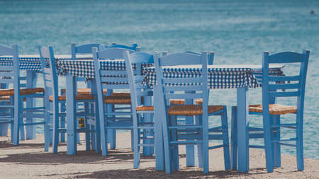Seaside blue table and chairs open cafe outdoor restaurant in Greece on sea shore. Summer vacation on resort.の写真素材