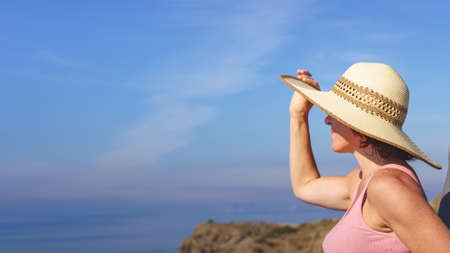 Mature woman in summer hat relaxing, enjoying coast view in Spain. Summer holidays.の写真素材