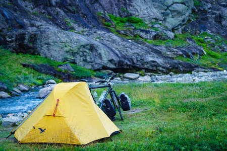 TROLLSTIGEN, NORWAY - JULY 27, 2018: Yellow camping tent and mountain bicycle on river shore, Trollstigen area in Norway.のeditorial素材