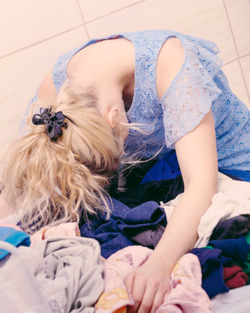 Unhappy woman in bathroom with pile of dirty clothes. Laundry concept. Hard work, dirty job,...