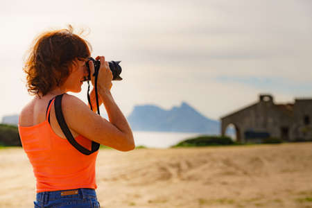 Female tourist on holidays taking photos with camera. Gibraltar rock on horizon. Torrecarbonera beach, Punta Mala, Andalusia Spain.の写真素材