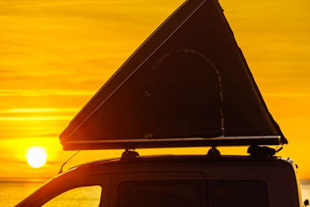 Car with roof top tent camping on mediterranean coast at sunrise. Holidays and traveling.の写真素材