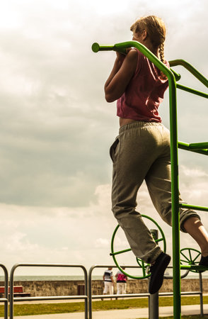 Active young woman exercising on ladder. Sporty fit girl in training suit working out at outdoor...