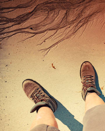 Male feet in hiking shoes on sandy beach. Summertime.の写真素材