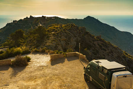 Camper van on parking area at Battery de Castillitos in Spain. Tourist attraction, castle fortification and military cannon for coast defense. Seascape at sunset.の写真素材