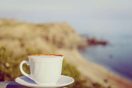 Coffee cup outdoors against sea beach background. Camping, vacation, lifestyle concept.の写真素材