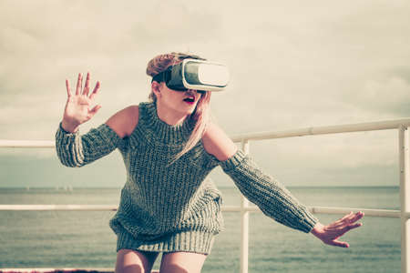 Young woman testing VR glasses outside. Female wearing virtual reality headset during spring weather,の写真素材
