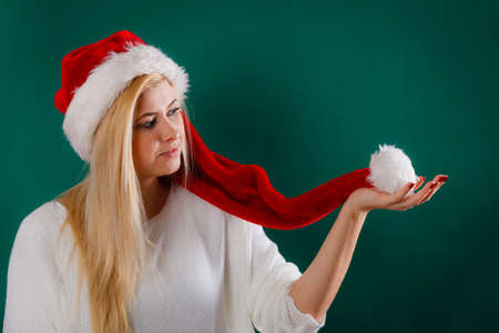 Woman wearing Santa Claus red hat waiting for Christmas gifts and holidays playing with pompom.の写真素材