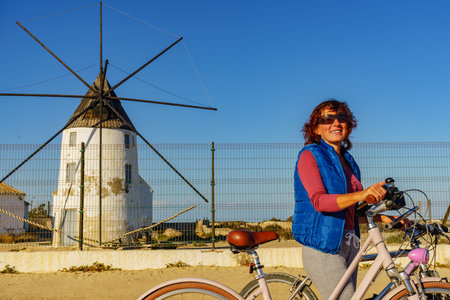 Mature woman with bicycle relaxing at San Pedro del Pinatar park, Murcia Spain. Tourist attraction....