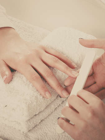 Woman hand on towel, beautician file nails. Beauty wellness spa treatment, manicure conceptの写真素材