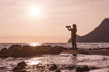 Female tourist with camera taking travel picture on Monsul beach. Cabo de Gata Nijar Natural Park, province Almeria, Andalusia, Spain.の写真素材