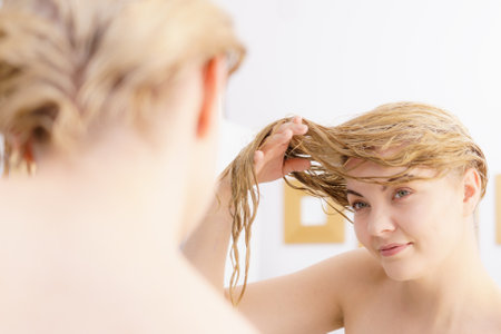 Woman having wet blonde hair. Young female about to wash her hairdoの写真素材