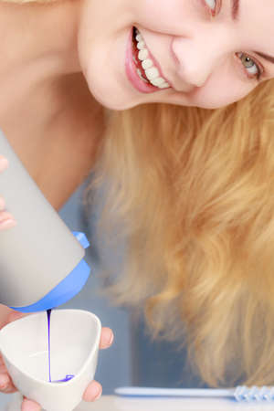 Woman pouring purple hair dye or shampoo toner into white bowl. Hygiene object concept.の写真素材