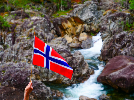 Tourist hand holding norwegian flag outdoor against rocks mountain natureの写真素材